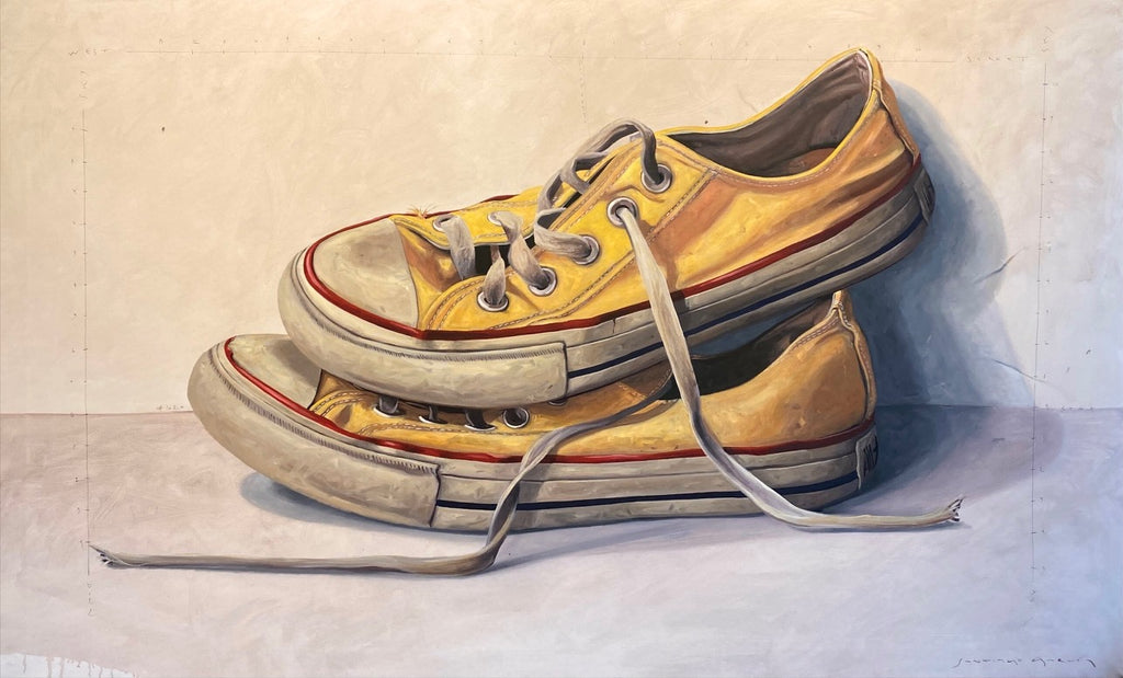 Closeup of a pair of converse resting on one another. Shoes are yellow and stacked