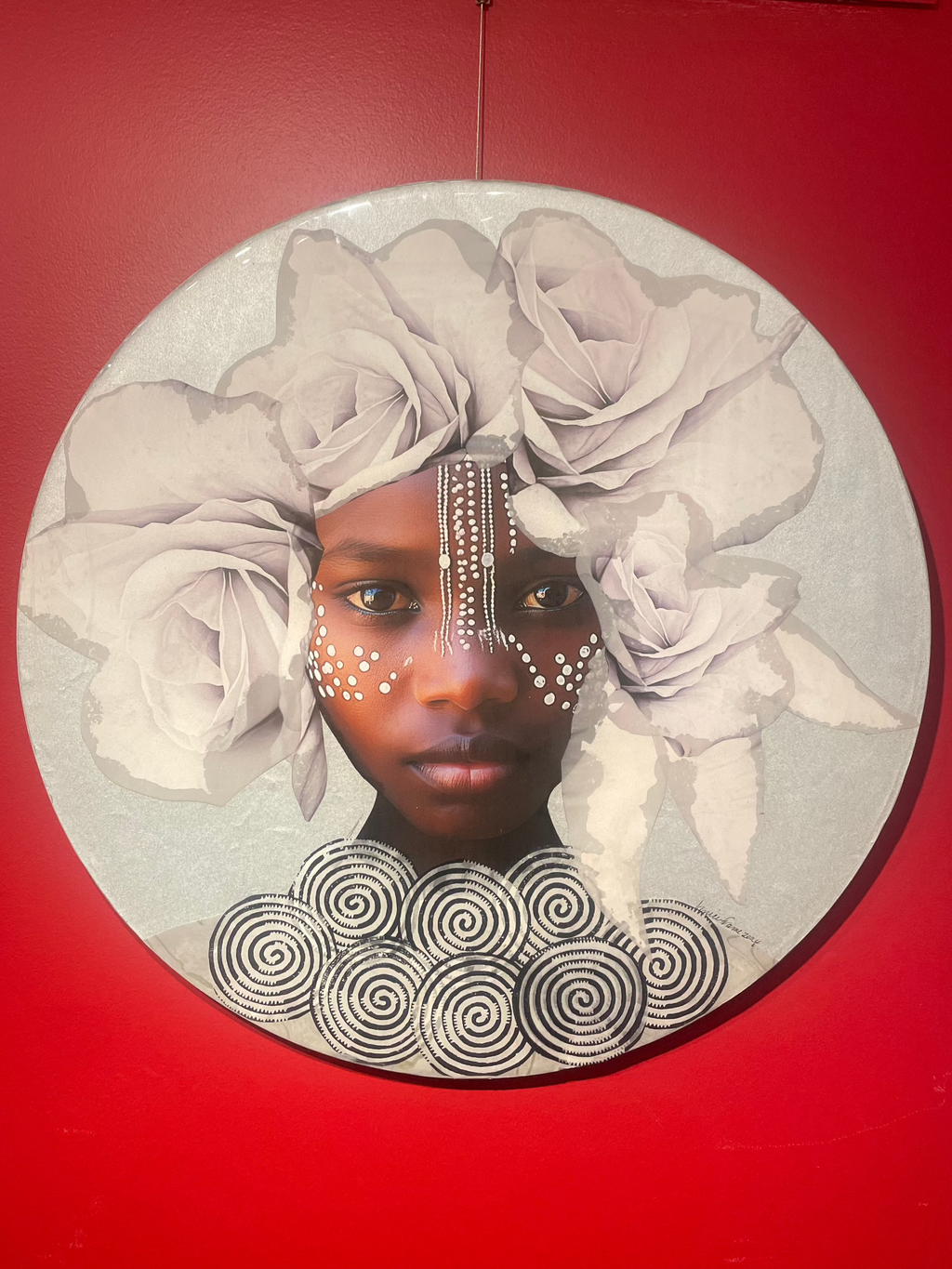 Young Black girl looking straight ahead adorned with a white flower crown, tribal markings, and a silver necklace.